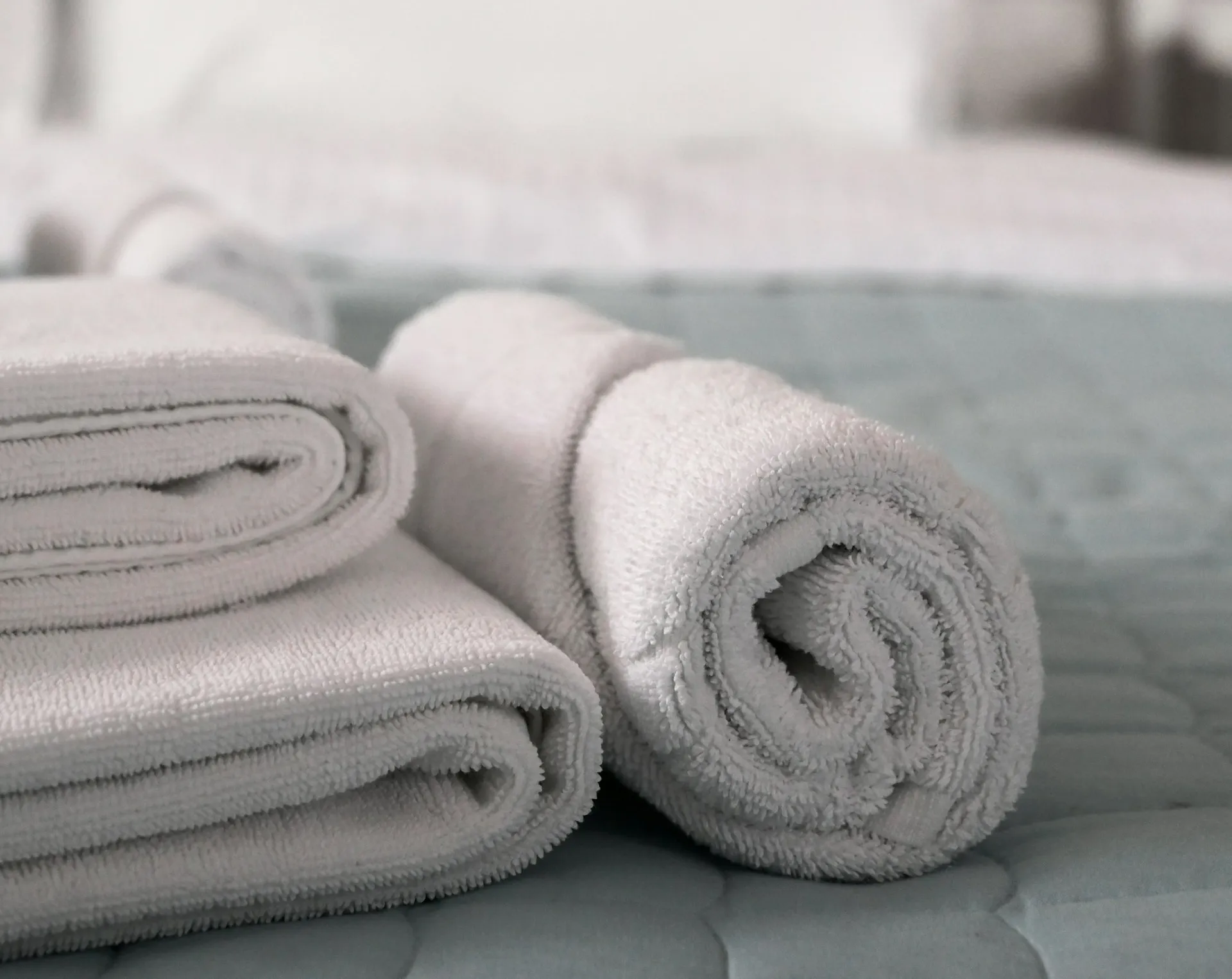 Neatly folded hotel linens stacked on shelving in a laundry room
